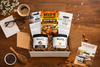 Top-down view of a Reid’s Gourmet subscription box featuring two peanut butter jars, recipe cards, and packaging inserts
