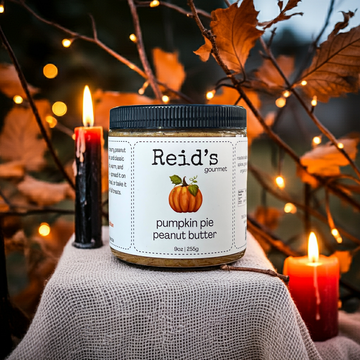 Jar of Reid's Gourmet pumpkin pie peanut butter with autumn decorations and candles in the background