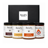 Four jars of Reid's Gourmet artisanal honey arranged in front of a black gift box on a white background. The jars include immunity boost, whipped honey, cinnamon whipped honey, and hot honey.
